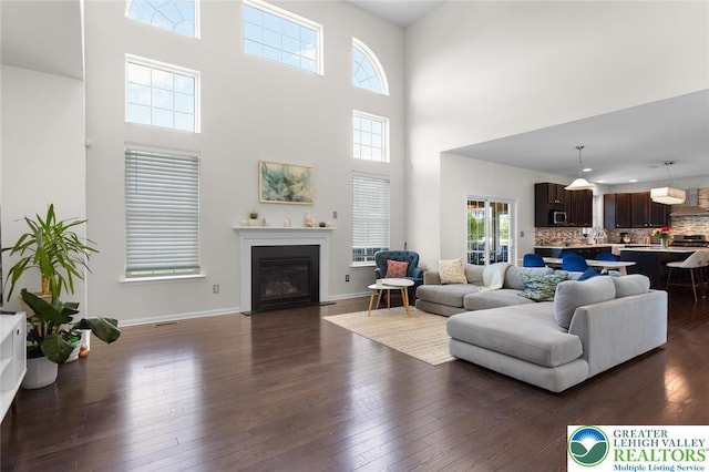 237 Danbury Dr, Upper Nazareth Twp, PA 18064 - living room featuring a towering ceiling, dark wood-style floors, healthy amount of natural light, and a fireplace with flush hearth