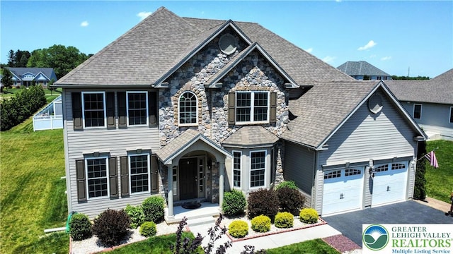 237 Danbury Dr, Upper Nazareth Twp, PA 18064 - view of front of house featuring stone siding, asphalt driveway, a garage, a front lawn, and a shingled roof