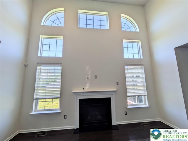 237 Danbury Dr, Upper Nazareth Twp, PA 18064 - unfurnished living room featuring a towering ceiling, a fireplace, and dark wood finished floors