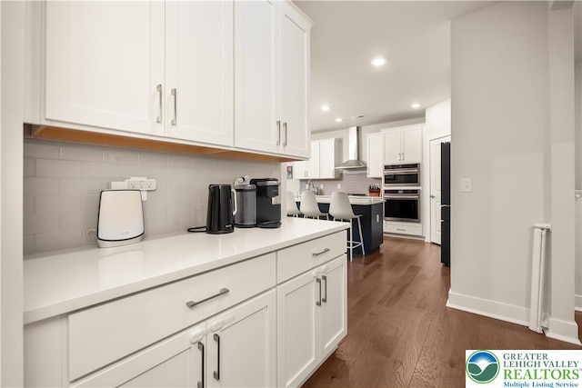5635 Saucon Ridge Rd, Upper Saucon Twp, PA 18036 - kitchen featuring double oven, wall chimney exhaust hood, white cabinetry, dark wood-type flooring, and backsplash