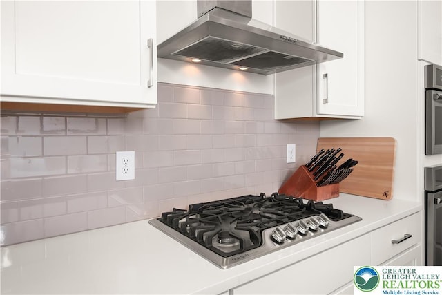 5635 Saucon Ridge Rd, Upper Saucon Twp, PA 18036 - kitchen featuring wall chimney exhaust hood, stainless steel appliances, white cabinets, light countertops, and backsplash