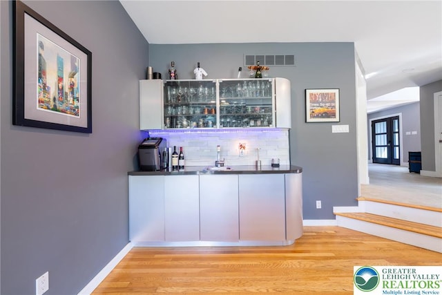 1488 Shelburne Ct, South Whitehall Twp, PA 18104 - indoor wet bar featuring decorative backsplash, light wood finished floors, and french doors