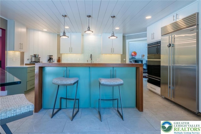 1488 Shelburne Ct, South Whitehall Twp, PA 18104 - kitchen with built in refrigerator, white cabinetry, a kitchen bar, recessed lighting, and decorative light fixtures