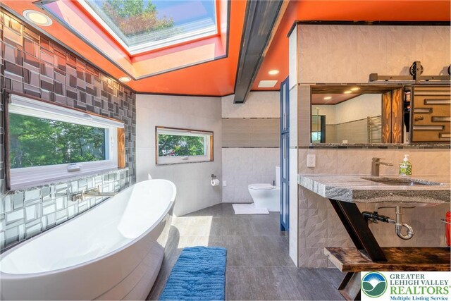 1488 Shelburne Ct, South Whitehall Twp, PA 18104 - full bathroom with a soaking tub, a skylight, tile walls, and tile patterned flooring