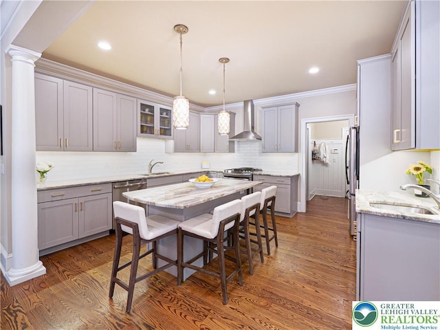 2063 Forge Run, Bethlehem City, PA 18015 - kitchen featuring wall chimney exhaust hood, gray cabinets, appliances with stainless steel finishes, a kitchen breakfast bar, and decorative columns