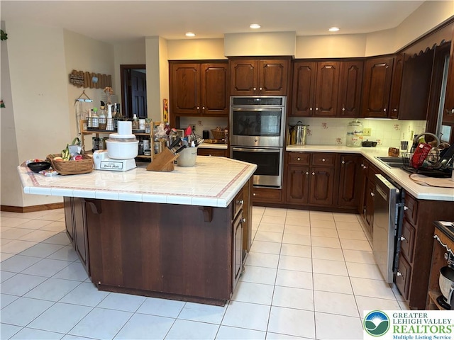 4804 Parkview Dr S, Lower Macungie Twp, PA 18049 - kitchen featuring stainless steel appliances, a center island, light tile patterned floors, dark brown cabinets, and tasteful backsplash