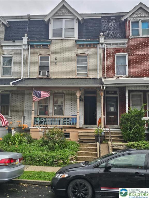 949 W Gordon St, Allentown City, PA 18102 - view of property featuring brick siding, cooling unit, covered porch, and mansard roof