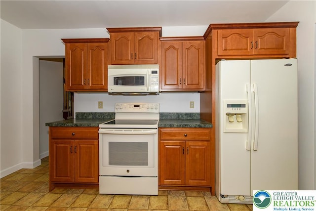 4015 Sycamore Dr, Lehigh Twp, PA 18067 - kitchen featuring white appliances, dark countertops, light stone finish flooring, and brown cabinetry