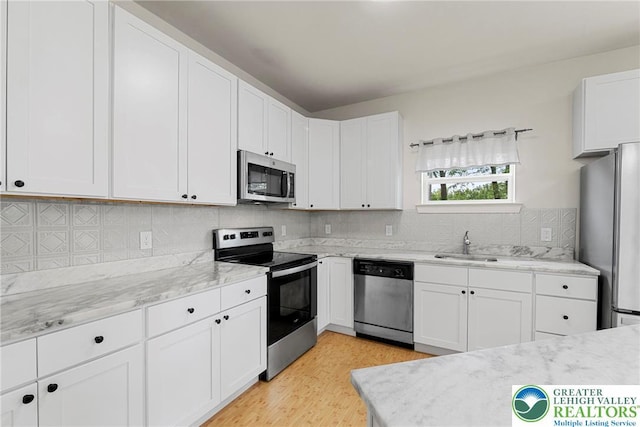 273 W Fairview St W, Bethlehem City, PA 18018 - kitchen featuring appliances with stainless steel finishes, light wood-style floors, white cabinetry, tasteful backsplash, and light stone counters