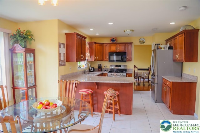 3104 Peacock Dr, Bethlehem Twp, PA 18020 - kitchen with stainless steel appliances, a peninsula, light countertops, light tile patterned floors, and a kitchen bar