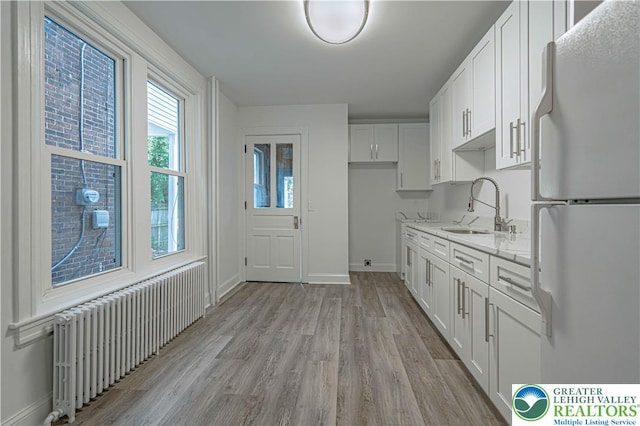 622 N Jefferson St, Allentown City, PA 18102 - kitchen featuring freestanding refrigerator, radiator, light wood-style flooring, and white cabinetry