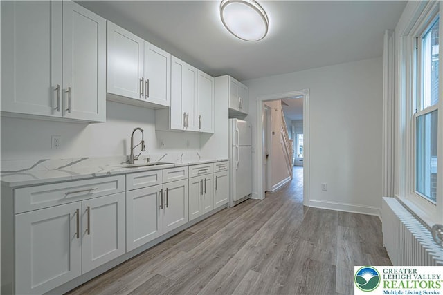 622 N Jefferson St, Allentown City, PA 18102 - kitchen with radiator, freestanding refrigerator, light wood-style floors, and white cabinets