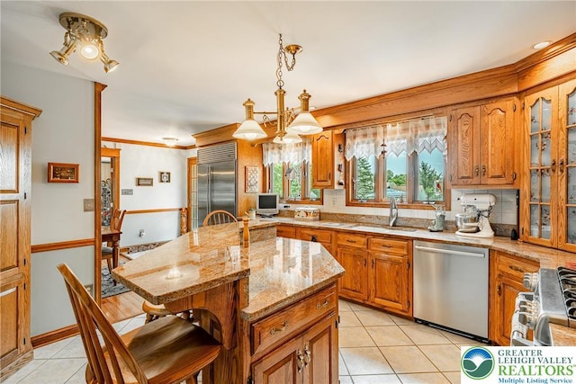 530 Station Rd, Richland Twp, PA 18951 - kitchen with appliances with stainless steel finishes, light tile patterned flooring, brown cabinets, a kitchen breakfast bar, and ornamental molding