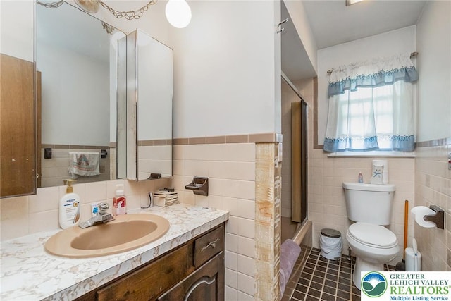 2057 Grove St, South Whitehall Twp, PA 18104 - bathroom featuring tile walls, vanity, a wainscoted wall, bath / shower combo with glass door, and tile patterned floors