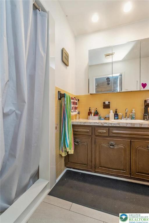2057 Grove St, South Whitehall Twp, PA 18104 - bathroom with double vanity, tile walls, tile patterned floors, curtained shower, and recessed lighting
