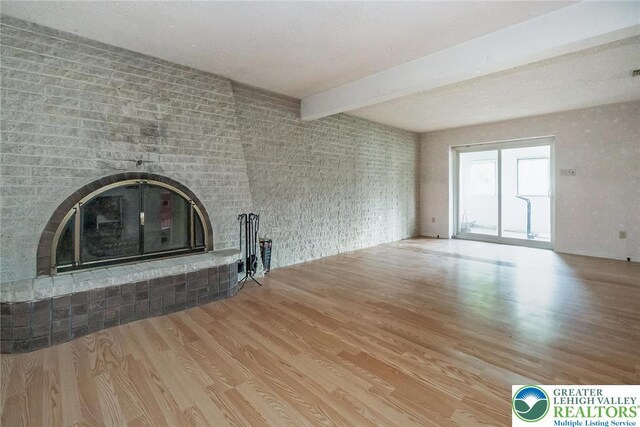 2057 Grove St, South Whitehall Twp, PA 18104 - unfurnished living room featuring a brick fireplace, wood finished floors, and beamed ceiling