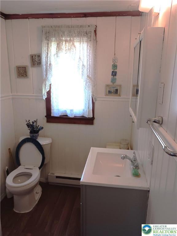 618 Mccabe Ln, Hamilton Twp, PA 18353 - half bathroom with a baseboard radiator, vanity, wood finished floors, and a decorative wall