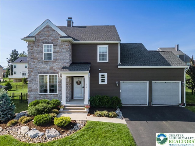 420 Rinaldi Ln, Forks Twp, PA 18040 - traditional-style home with stone siding, an attached garage, asphalt driveway, a chimney, and roof with shingles