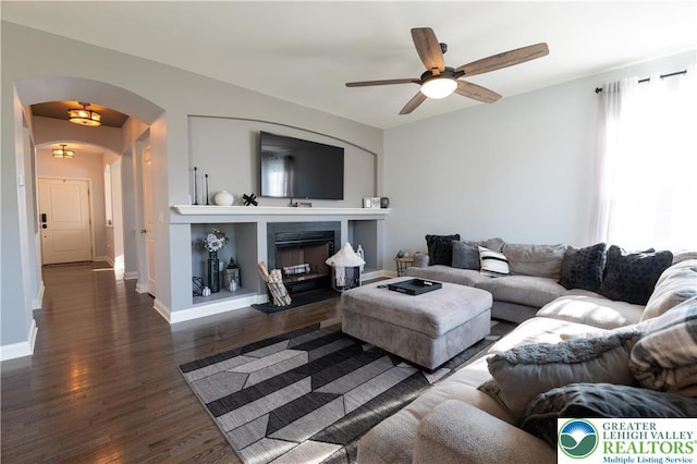420 Rinaldi Ln, Forks Twp, PA 18040 - living area with arched walkways, wood finished floors, ceiling fan, and a fireplace with raised hearth