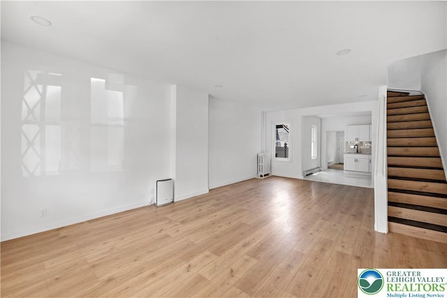 907 N 5th St, Allentown City, PA 18102 - unfurnished living room with radiator, stairway, light wood-type flooring, and a baseboard heating unit