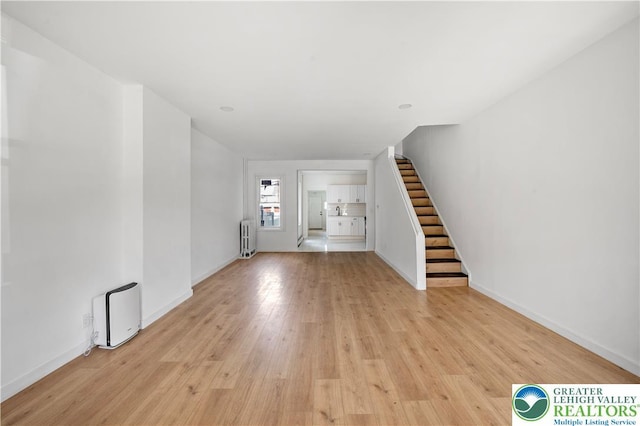 907 N 5th St, Allentown City, PA 18102 - unfurnished living room with radiator heating unit, stairway, and light wood-style flooring