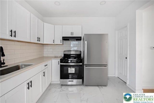 907 N 5th St, Allentown City, PA 18102 - kitchen featuring appliances with stainless steel finishes, ventilation hood, white cabinets, light marble finish flooring, and light countertops