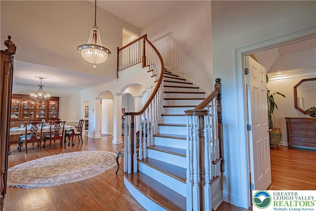 2650 Eagle Ln, Lower Saucon Twp, PA 18055 - stairway with arched walkways, decorative columns, wood finished floors, a chandelier, and crown molding