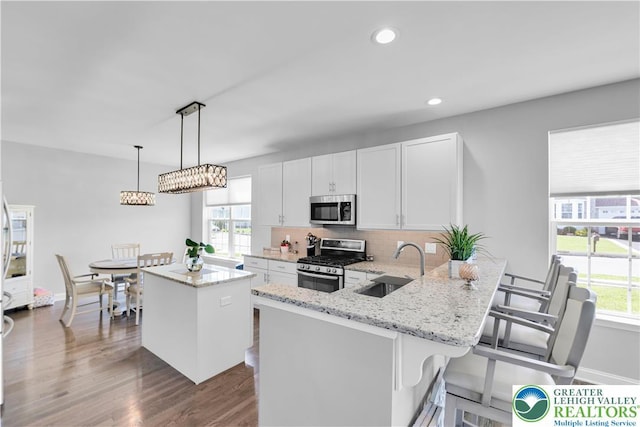 2835 Lenape, Forks Twp, PA 18040 - kitchen with appliances with stainless steel finishes, a kitchen island, decorative backsplash, dark wood-style floors, and white cabinets