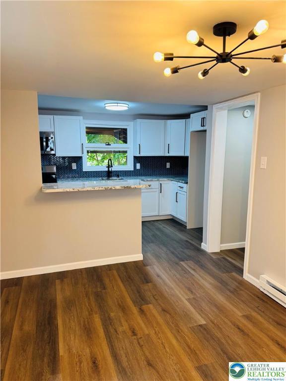 332 W Patterson St, Lansford Boro, PA 18232 - kitchen with stainless steel microwave, backsplash, dark wood finished floors, a chandelier, and white cabinetry