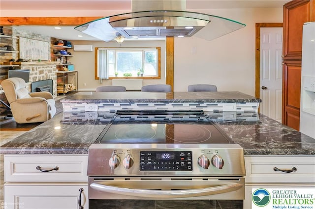 236 Moorestown Rd, Bushkill Twp, PA 18091 - kitchen with stainless steel electric range, open floor plan, dark stone counters, a stone fireplace, and white cabinets