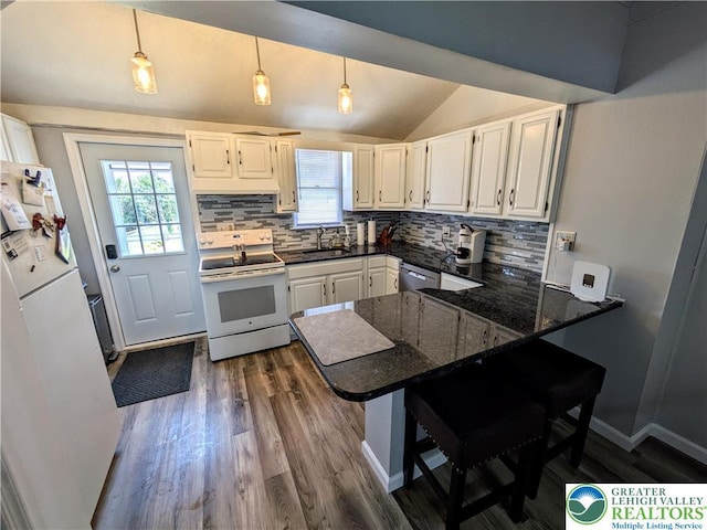 135 N 2nd St, Coplay Boro, PA 18037 - kitchen with white appliances, a peninsula, lofted ceiling, decorative backsplash, and dark wood-type flooring