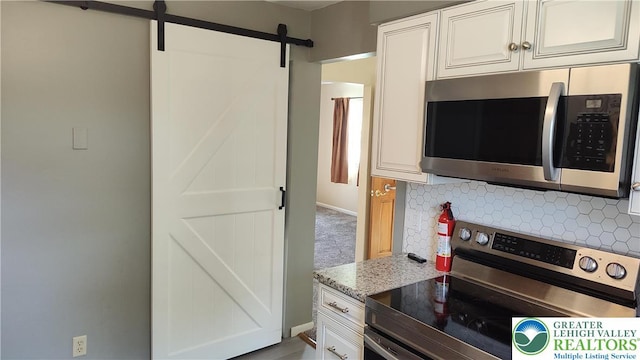 5278 Herman St, Heidelberg Twp, PA 18053 - kitchen featuring stainless steel appliances, a barn door, tasteful backsplash, light stone countertops, and white cabinetry