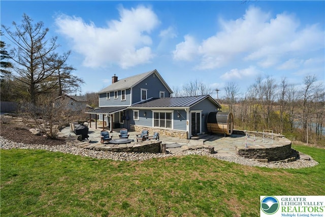 3224 Middle Easton Belmont Pike, Hamilton Twp, PA 18360 - back of property featuring a fire pit, a patio area, a standing seam roof, a metal roof, and a chimney