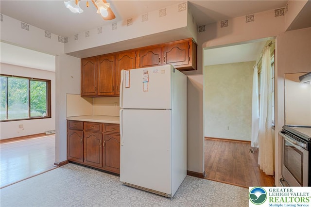 4834 Maple St, Lower Mt Bethel Twp, PA 18013 - kitchen with freestanding refrigerator, stainless steel range oven, brown cabinetry, and light countertops
