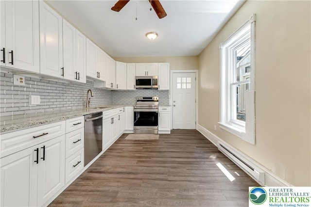 1744 W Chew St, Allentown City, PA 18104 - kitchen featuring appliances with stainless steel finishes, a baseboard heating unit, decorative backsplash, a ceiling fan, and white cabinetry