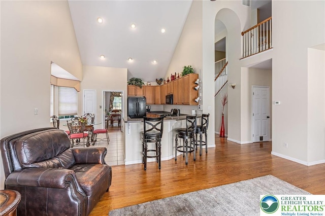441 Sawgrass Dr, Upper Macungie Twp, PA 18104 - kitchen featuring open floor plan, high vaulted ceiling, black appliances, wood finished floors, and a peninsula