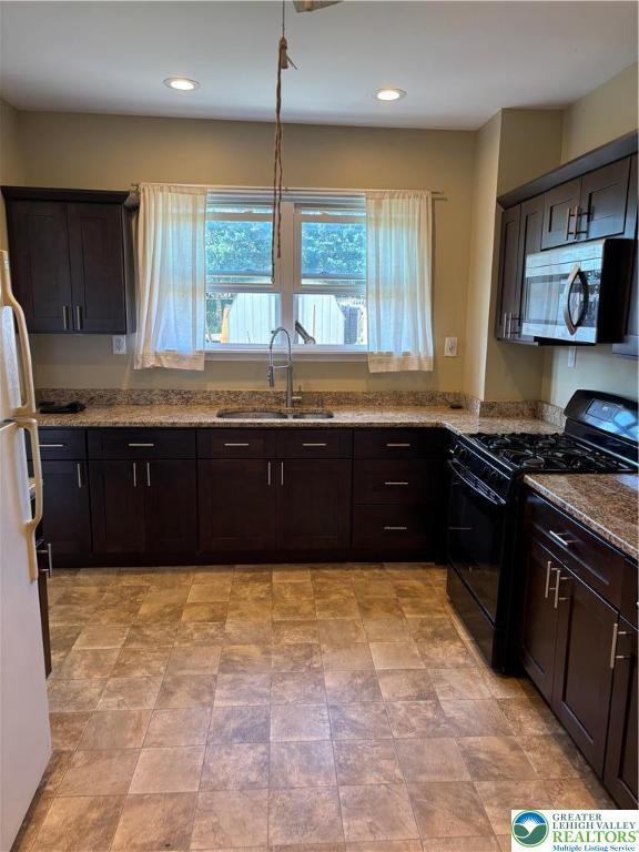 232 W Nesquehoning St, Easton, PA 18042 - kitchen with black gas range, stainless steel microwave, light stone counters, freestanding refrigerator, and recessed lighting