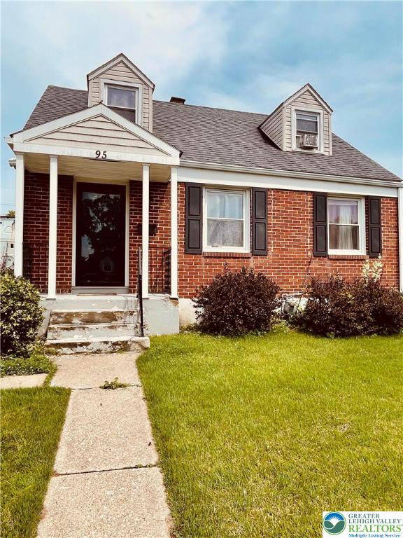 95 7th St, Whitehall Twp, PA 18052 - view of front facade with brick siding, a front yard, and a shingled roof