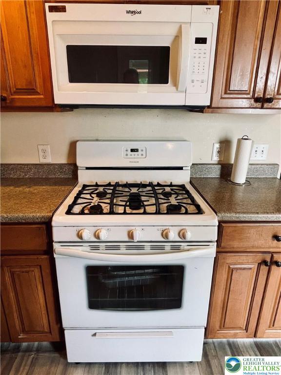 95 7th St, Whitehall Twp, PA 18052 - kitchen featuring white appliances, wood finished floors, brown cabinets, and dark countertops