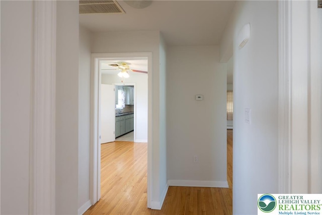 hallway with light wood-style flooring and baseboards