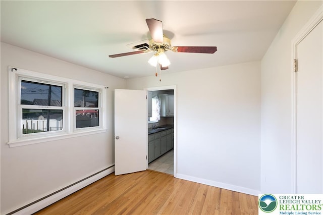 empty room with baseboard heating, ceiling fan, and light wood-type flooring
