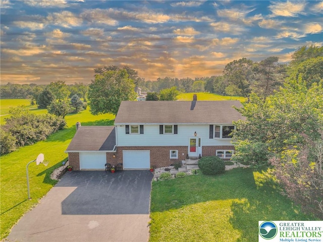 70 Faust N Rd, Pa, PA 19507 - bi-level home with brick siding, a yard, driveway, and view of wooded area