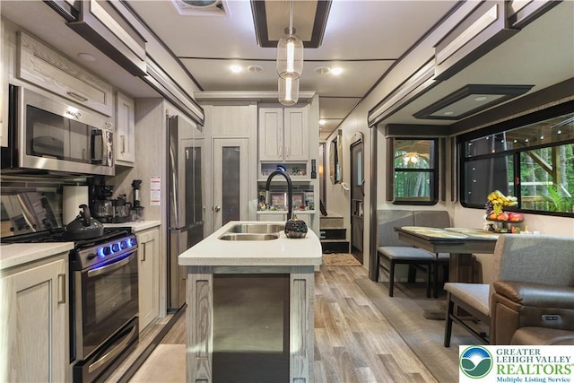 149 Deer Path Ln, Tobyhanna Twp, PA 18346 - kitchen with appliances with stainless steel finishes, light countertops, a center island with sink, light wood finished floors, and hanging light fixtures