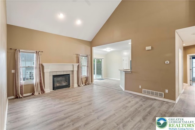 620 Pittston Ave, Luzerne, PA 18641 - unfurnished living room with high vaulted ceiling, a tiled fireplace, and light wood-type flooring