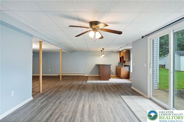 620 Pittston Ave, Luzerne, PA 18641 - unfurnished living room with a baseboard heating unit, wood finished floors, a paneled ceiling, a ceiling fan, and bar area