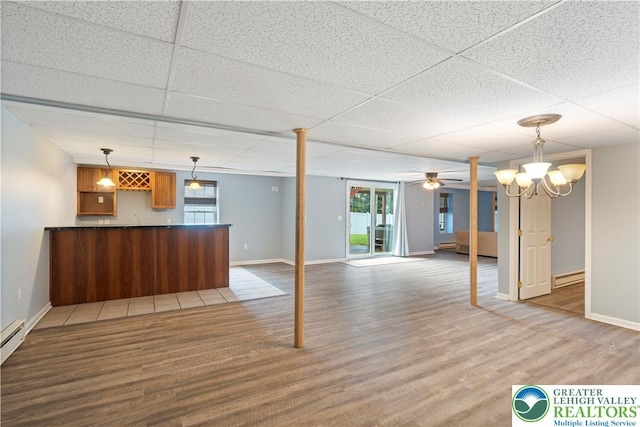 620 Pittston Ave, Luzerne, PA 18641 - unfurnished living room with baseboard heating, wood finished floors, bar with sink, a paneled ceiling, and ceiling fan