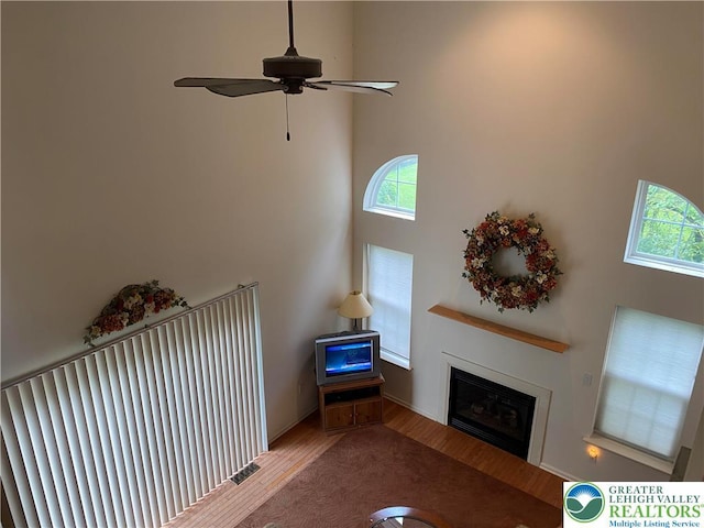 120 Palomino Cir, Washington Twp, PA 18013 - living area with wood finished floors, a glass covered fireplace, plenty of natural light, a towering ceiling, and a ceiling fan