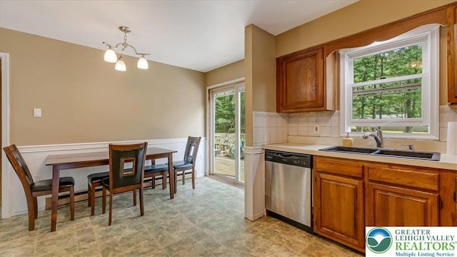 671 Dotters Corner Rd, Polk Twp, PA 18058 - kitchen featuring stainless steel dishwasher, brown cabinetry, light countertops, a wainscoted wall, and backsplash