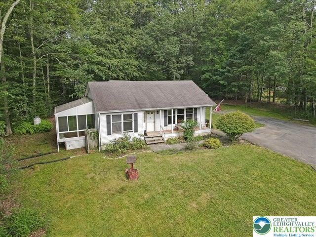 671 Dotters Corner Rd, Polk Twp, PA 18058 - view of front of house featuring a front lawn, a wooded view, a porch, and a sunroom