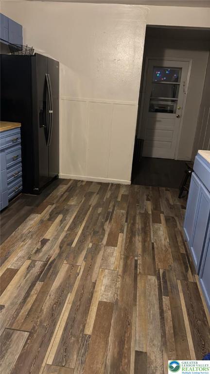 838 E Patterson St, Lansford Boro, PA 18232 - kitchen with black fridge with ice dispenser, dark wood-style floors, blue cabinetry, a decorative wall, and wainscoting